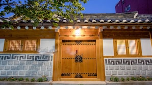 Edifici de fusta tradicional amb una porta de fusta gran, motius decoratius a les parets i un teulat d'àmples rajoles.