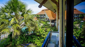 A lush garden with palm trees and a view of a building with a tiled roof.