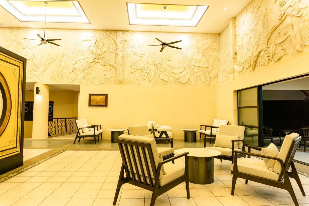 A lobby with a ceiling fan, a large wall mural, and seating arrangements.