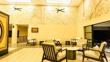 A lobby with a ceiling fan, a large wall mural, and seating arrangements.