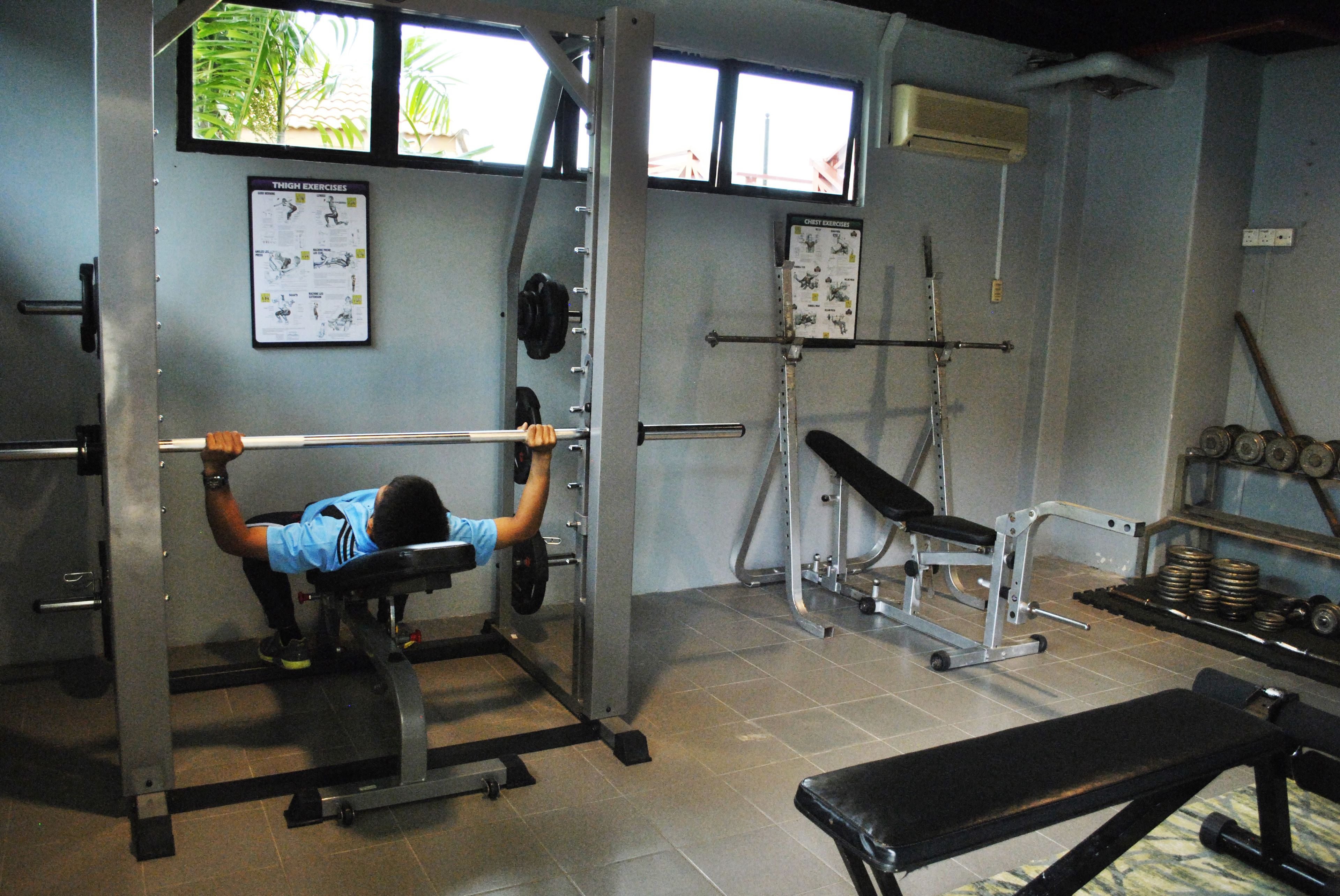 A gym with a bench press, squat rack, and various weights.