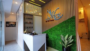 Un espace d’accueil au design moderne, comprenant un comptoir de réception, un mur végétal et un décor mural en panneaux de bois.