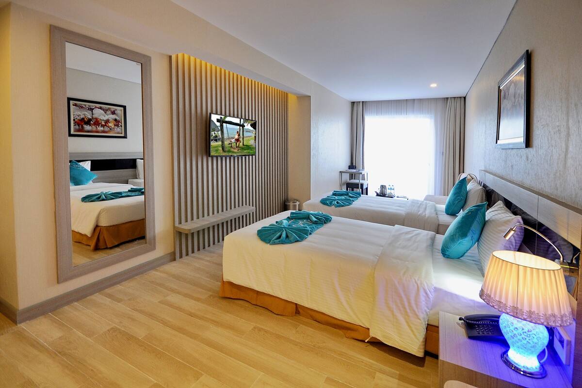Habitación de hotel con dos camas, un televisor, una lámpara y un espejo grande.