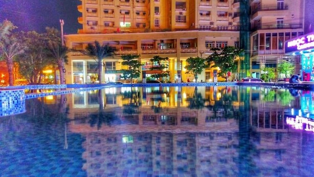 Un hôtel doté d’une piscine, de plusieurs étages et d’une enseigne lumineuse au néon.