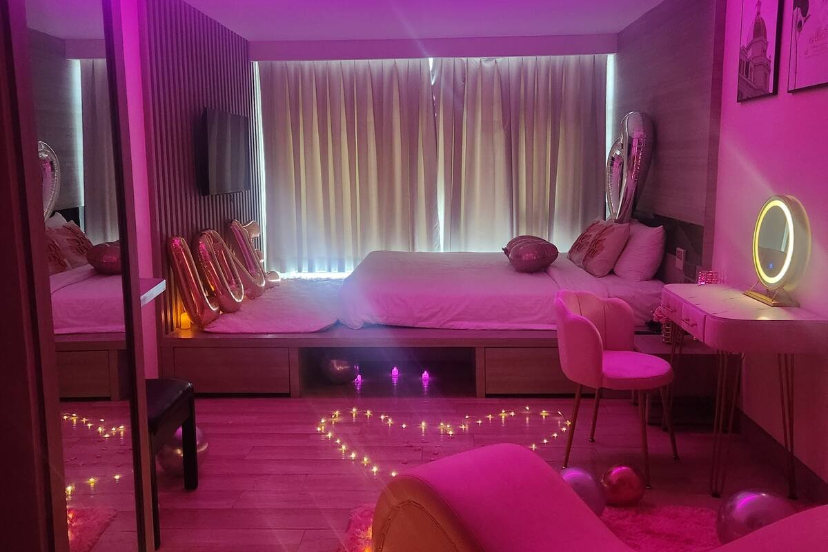 Un dormitorio moderno con cama, mesitas de noche, un escritorio y una silla.