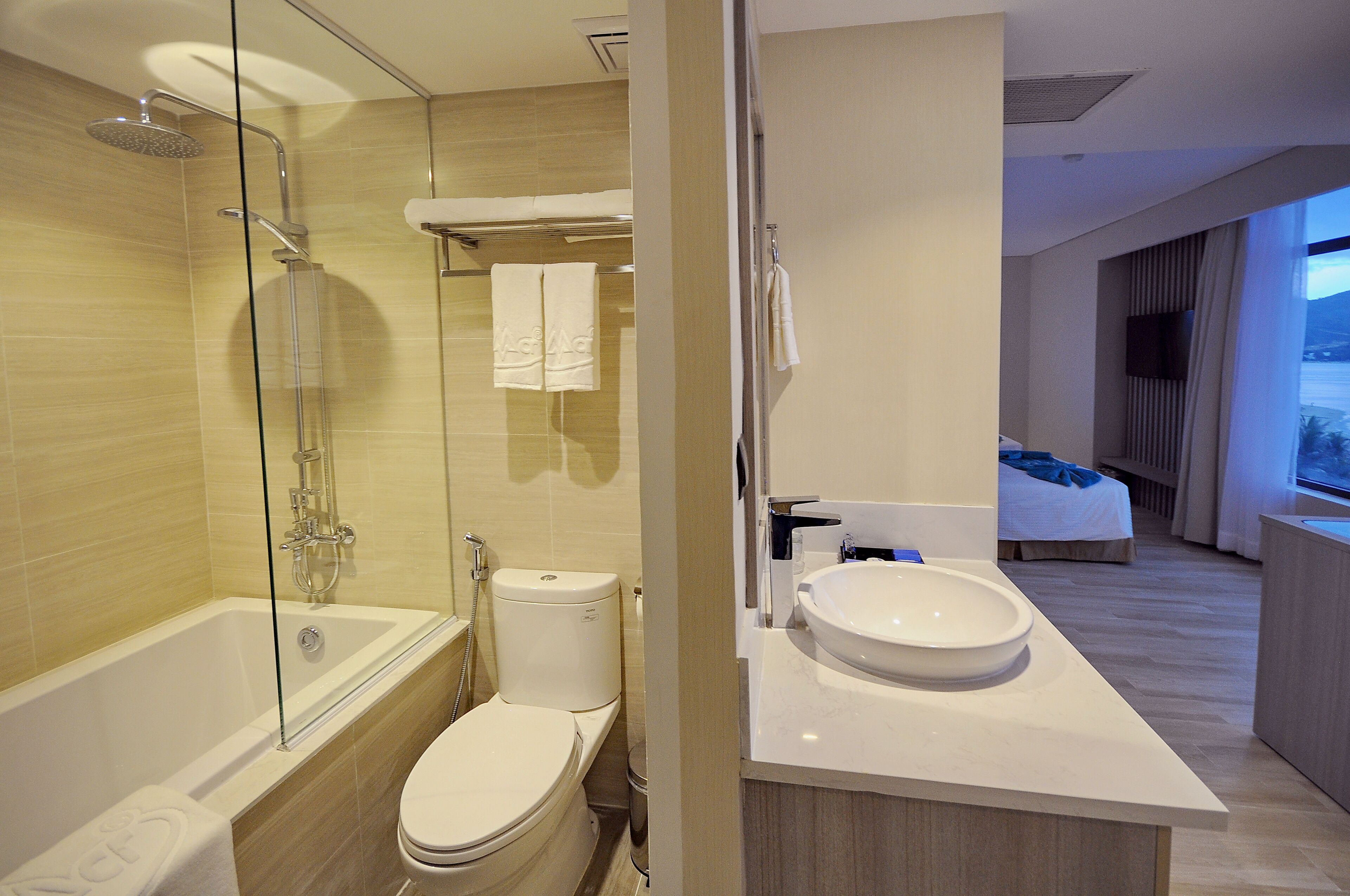 A modern bathroom with a glass-enclosed shower, a toilet, and a sink with a mirror.