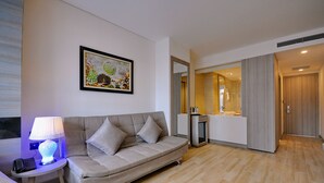 Un salon moderne avec un canapé, une lampe et une œuvre d’art encadrée accrochée au mur.