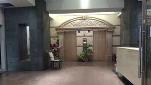 Et receptionområde med en bordplade i marmor, en stol, en potteplante og en elevator.
