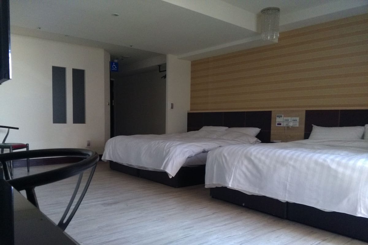 A hotel room with two beds, a desk, and a chair.