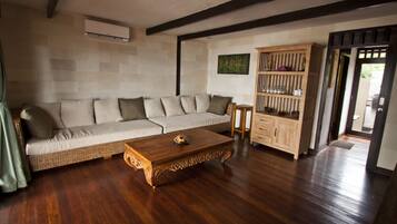 Una sala de estar con sofá, mesa de centro de madera y aparador.