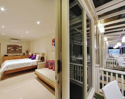 Un dormitorio con cama, sofá y balcón con vista a la playa.
