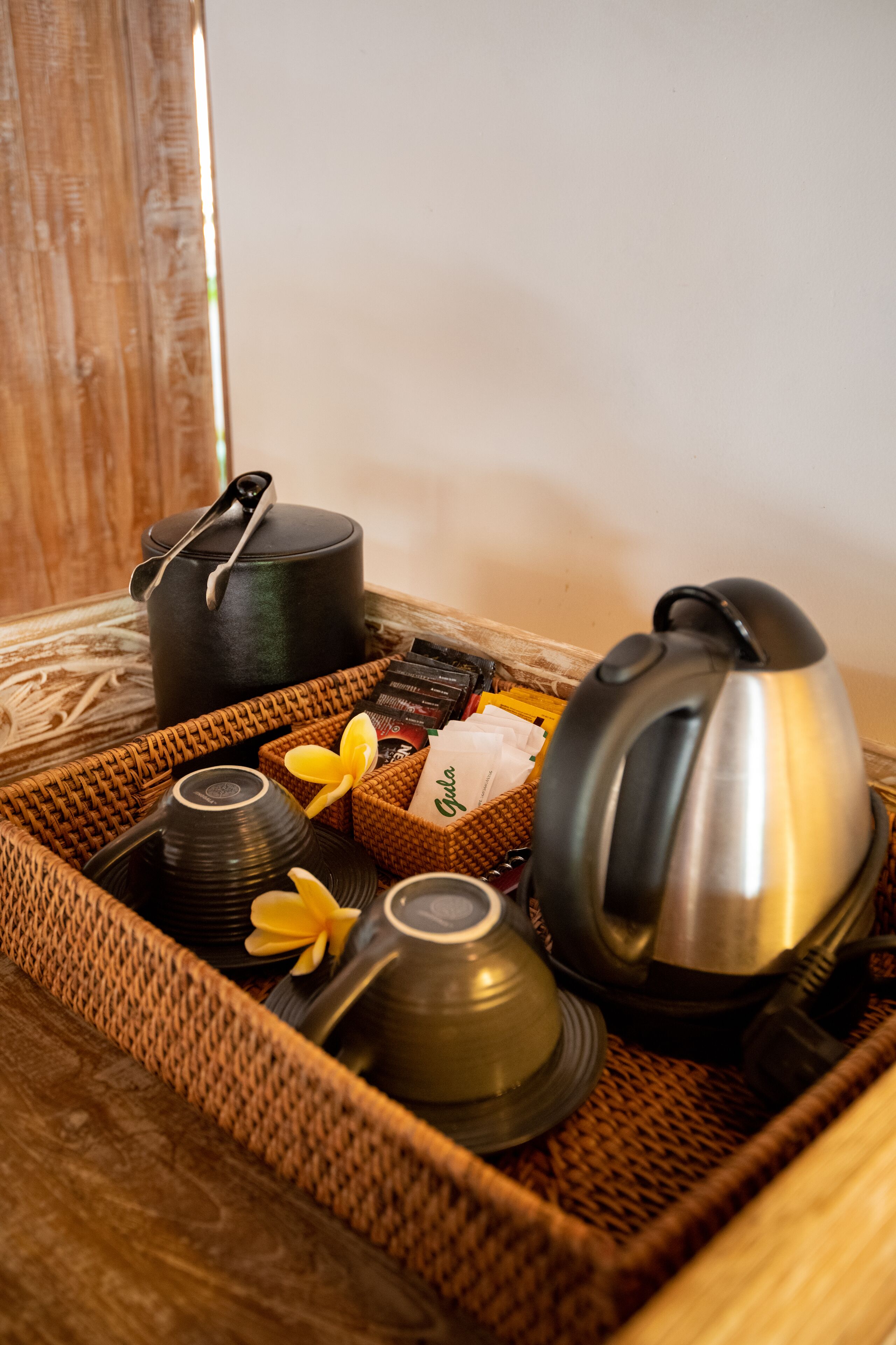 A wicker tray with tea sets and a teapot.
