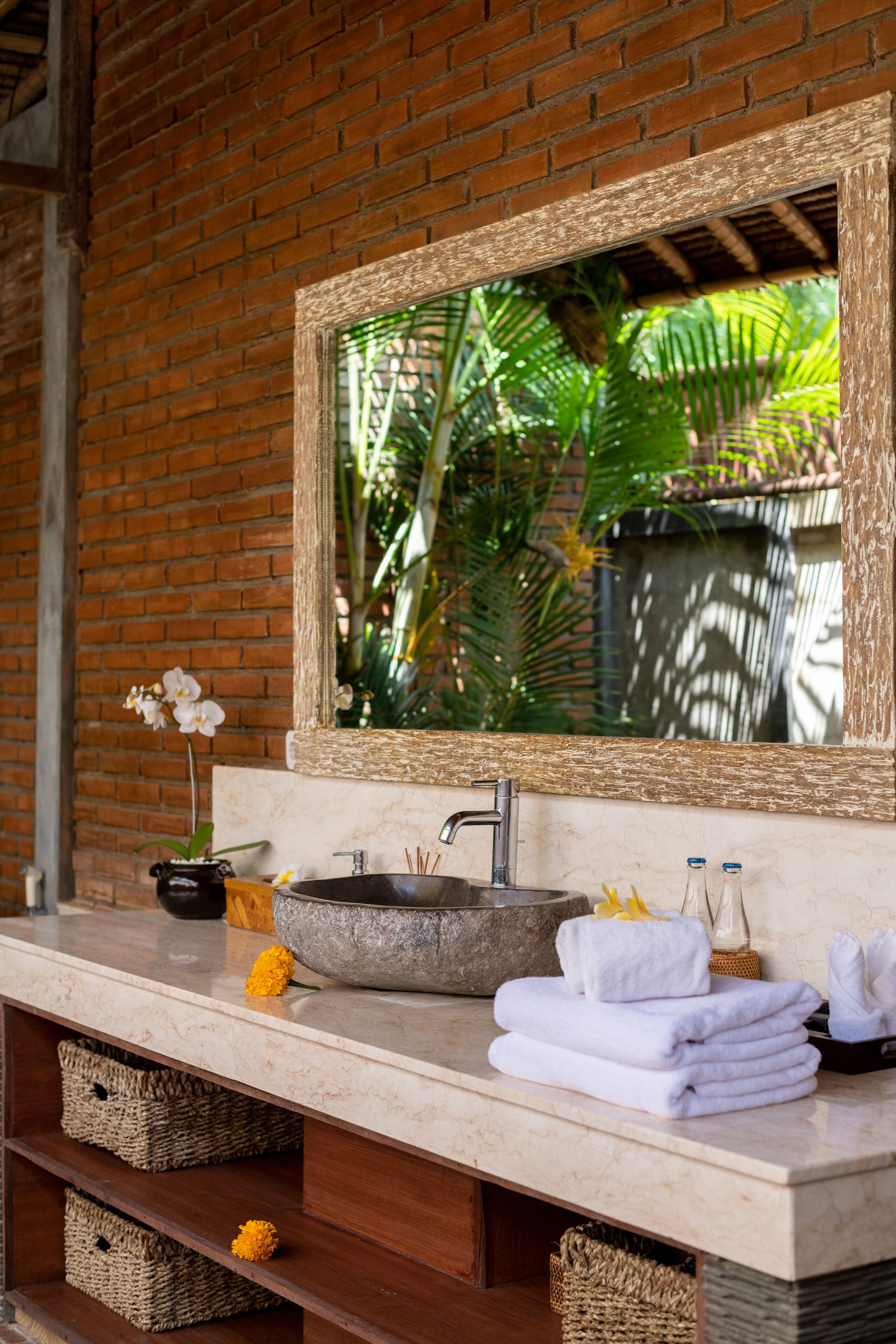 A bathroom with a stone sink, a large mirror, and a wooden vanity.