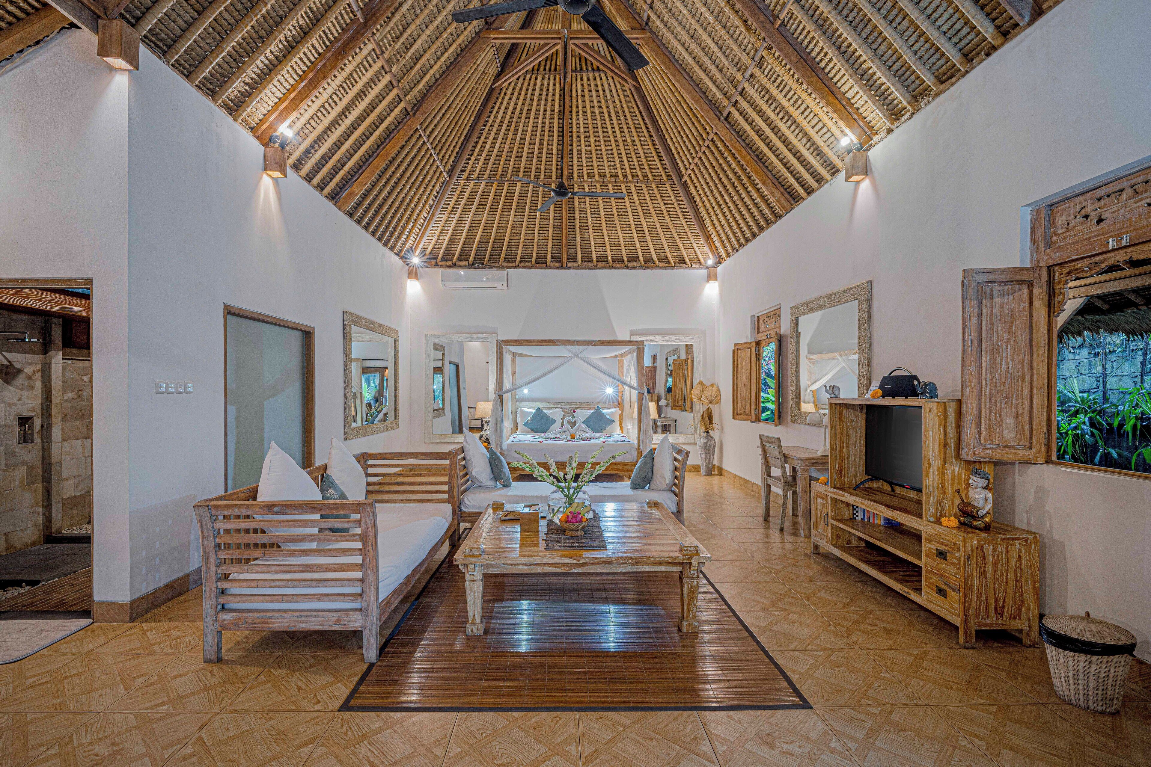 A spacious living area with a high ceiling, wooden furniture, and a television.