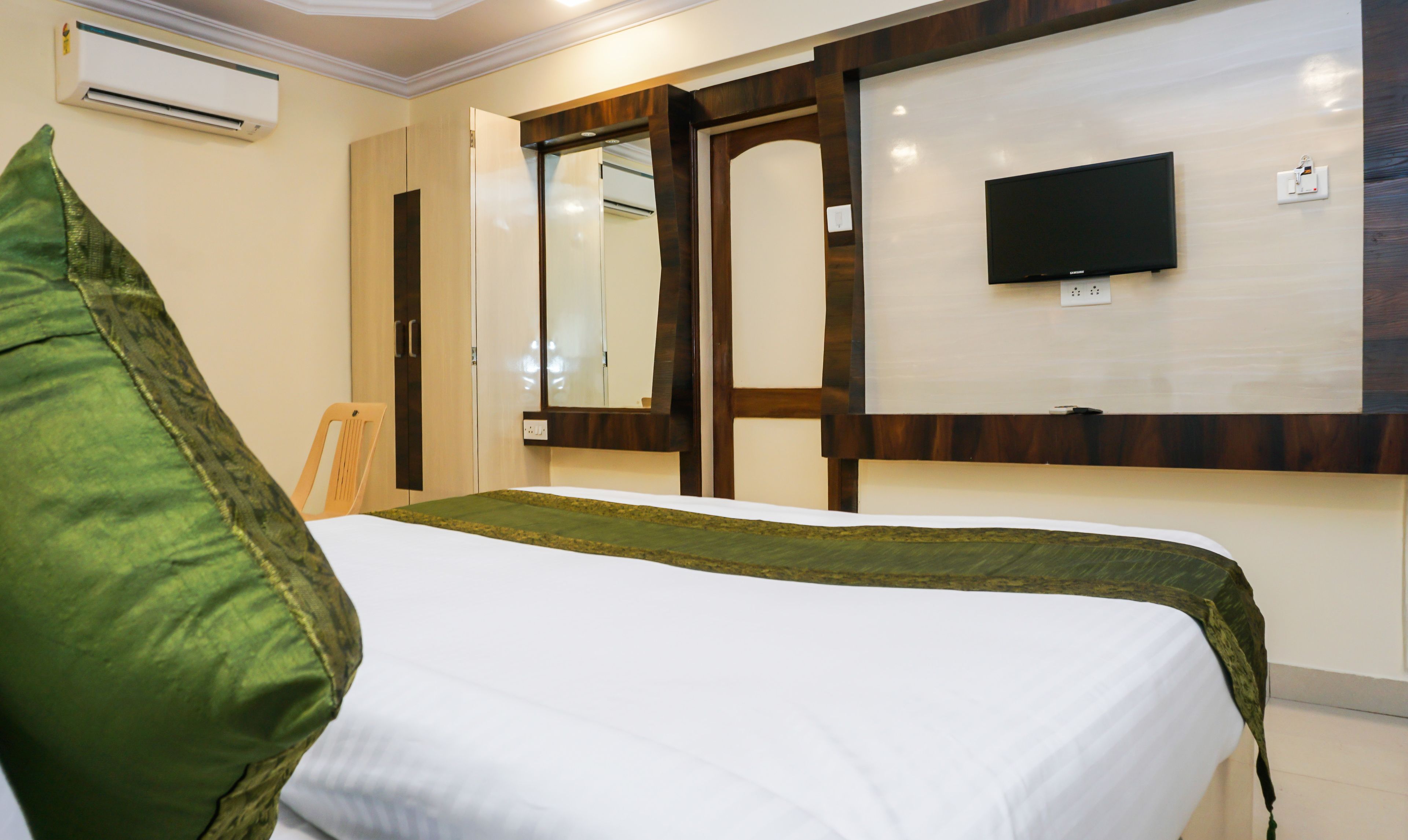 A hotel room with a bed, a television, and a wardrobe.