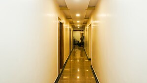 A long, narrow hallway with a shiny floor and walls painted in a light color. - Treebo Hillway Inn Main Market (Mahabaleshwar)