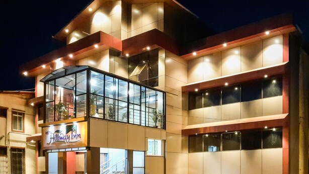 A hotel with a glass facade, multiple floors, and a sign for Hillway Inn. - Treebo Hillway Inn Main Market (Mahabaleshwar)