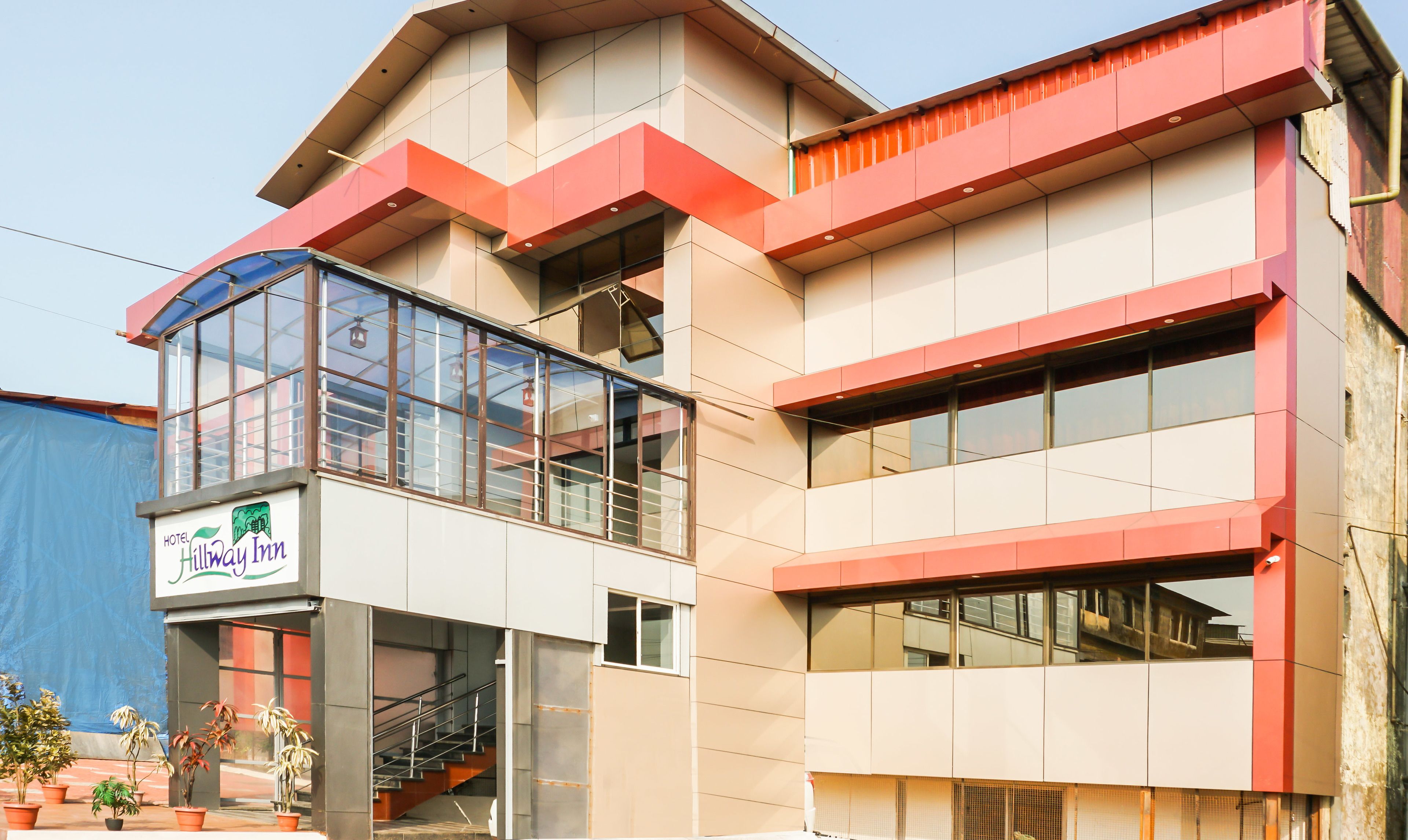 Un hôtel moderne avec une entrée en verre, un escalier et une enseigne indiquant « Hillway Inn ».