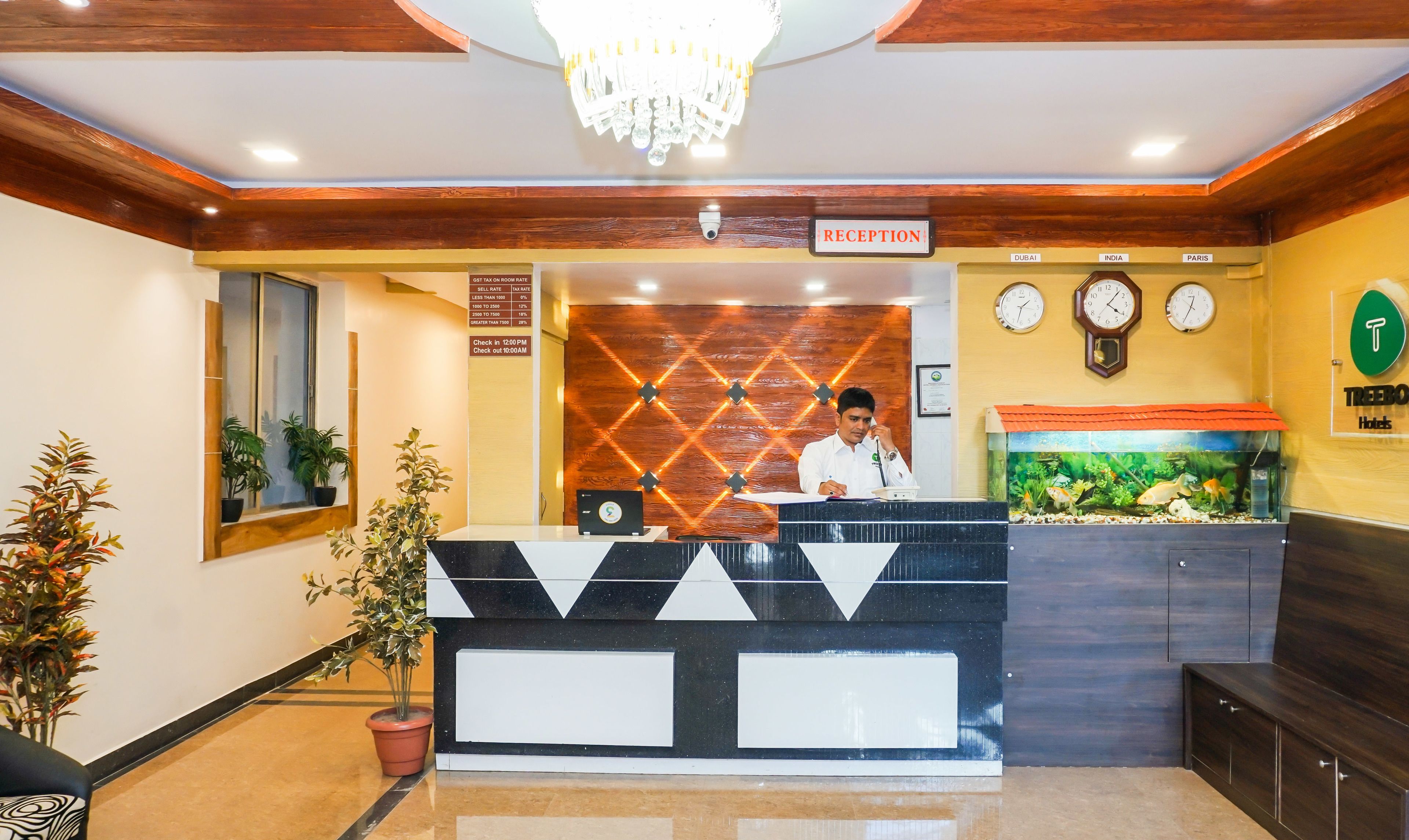 A reception desk with a sign indicating a reception area, a clock, and a wall-mounted aquarium.
