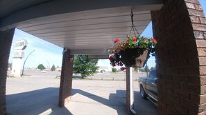 A covered outdoor area with hanging flower baskets, a Vulcan Inn sign, and a brick wall.
