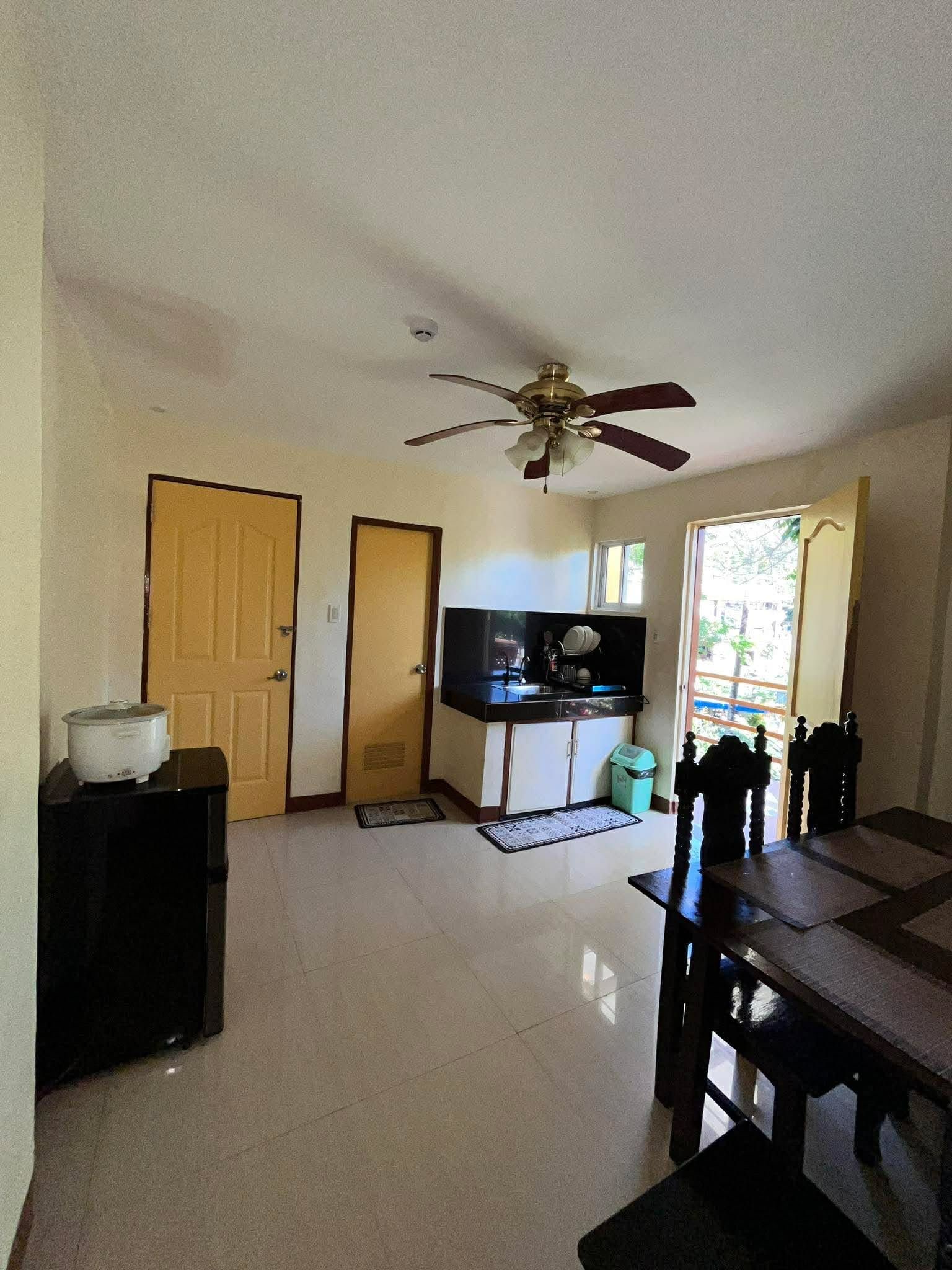 Un espacio habitable compacto con kitchenette, comedor y ventilador de techo.