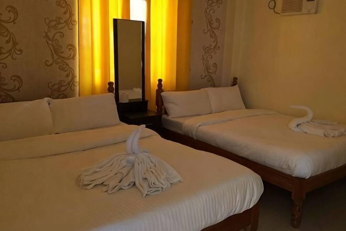 Two single beds with white linens and towels, a wooden headboard, and a mirror on the wall.