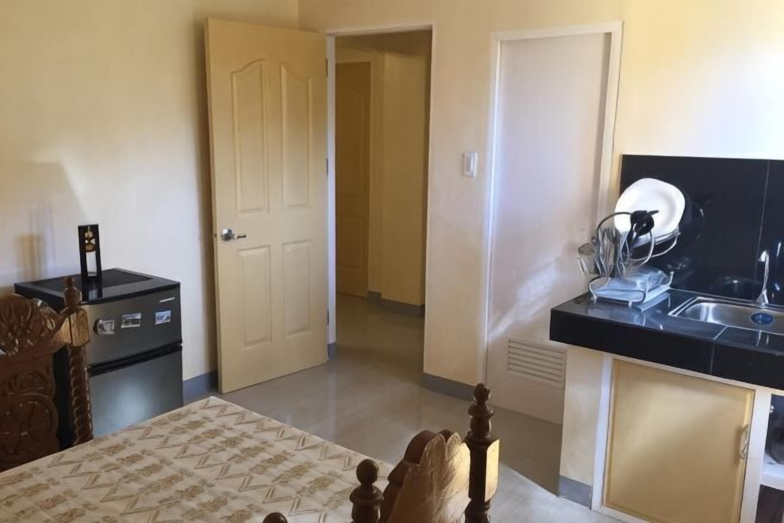 Um quarto com uma cama, uma cômoda e uma porta que dá para um corredor.