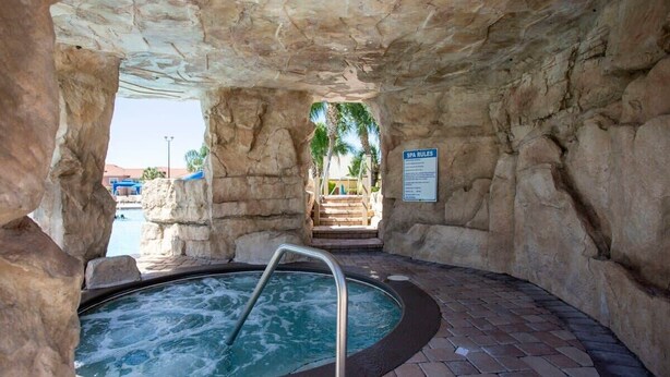 Un área de spa con un jacuzzi, paredes de piedra y un cartel que indica las normas del spa.
