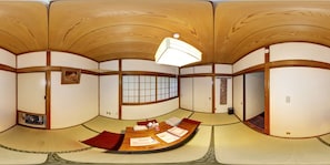 Una habitación japonesa tradicional con suelo de tatami, una mesa baja de madera y puertas correderas.