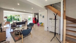 A spacious living area with a sofa, chairs, a dining table, and a staircase. - Wonderful private villa for 8 people with WIFI, TV, terrace and pets allowed (Saint-philibert)