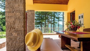 A wooden bench with a straw hat, a table with a vase of flowers, and a view of trees and mountains. - Beautiful apartment for 4 guests with pool, WIFI, TV, terrace and pets allowed (Senj)