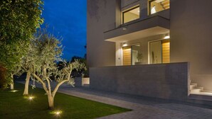 Un bâtiment moderne à deux étages, doté d’une entrée bien éclairée et d’un chemin pavé menant à la porte.