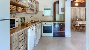A compact kitchen with wooden cabinets, a microwave, a Bosch oven, and a sink.