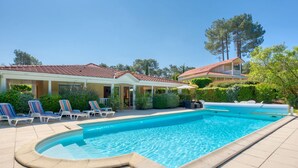 A swimming pool with lounge chairs and a covered patio area. - Stunning private villa for 8 guests with private pool, WIFI, TV and terrace (Lacanau-océan)