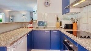 A modern kitchen with blue cabinets, a granite countertop, a built-in dishwasher, a stove, and a microwave. - Stunning private villa for 8 guests with private pool, WIFI, TV and terrace (Lacanau-océan)