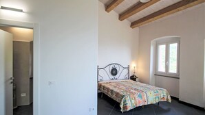 A bedroom with a bed, a window, and a door leading to a bathroom. - Stunning private villa for 4 guests with A/C, TV, terrace and pets allowed (Zoagli)