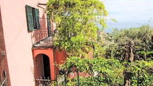 A pink building with green shutters, a balcony, and a view of a town. - Stunning private villa for 4 guests with A/C, TV, terrace and pets allowed (Zoagli)