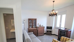A living room with a sofa, a patterned armchair, a cabinet, a television, and a fireplace. - Stunning private villa for 4 guests with A/C, TV, terrace and pets allowed (Zoagli)