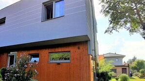 Ein modernes, zweistöckiges Haus mit Holzfassade, einem Fenster und einem gepflegten Rasen mit Pool.