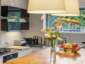 A modern kitchen with a wooden countertop, a Bosch toaster, a coffee maker, and a window with a view of greenery.
