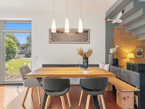 A modern dining area with a wooden table, four chairs, and pendant lighting.