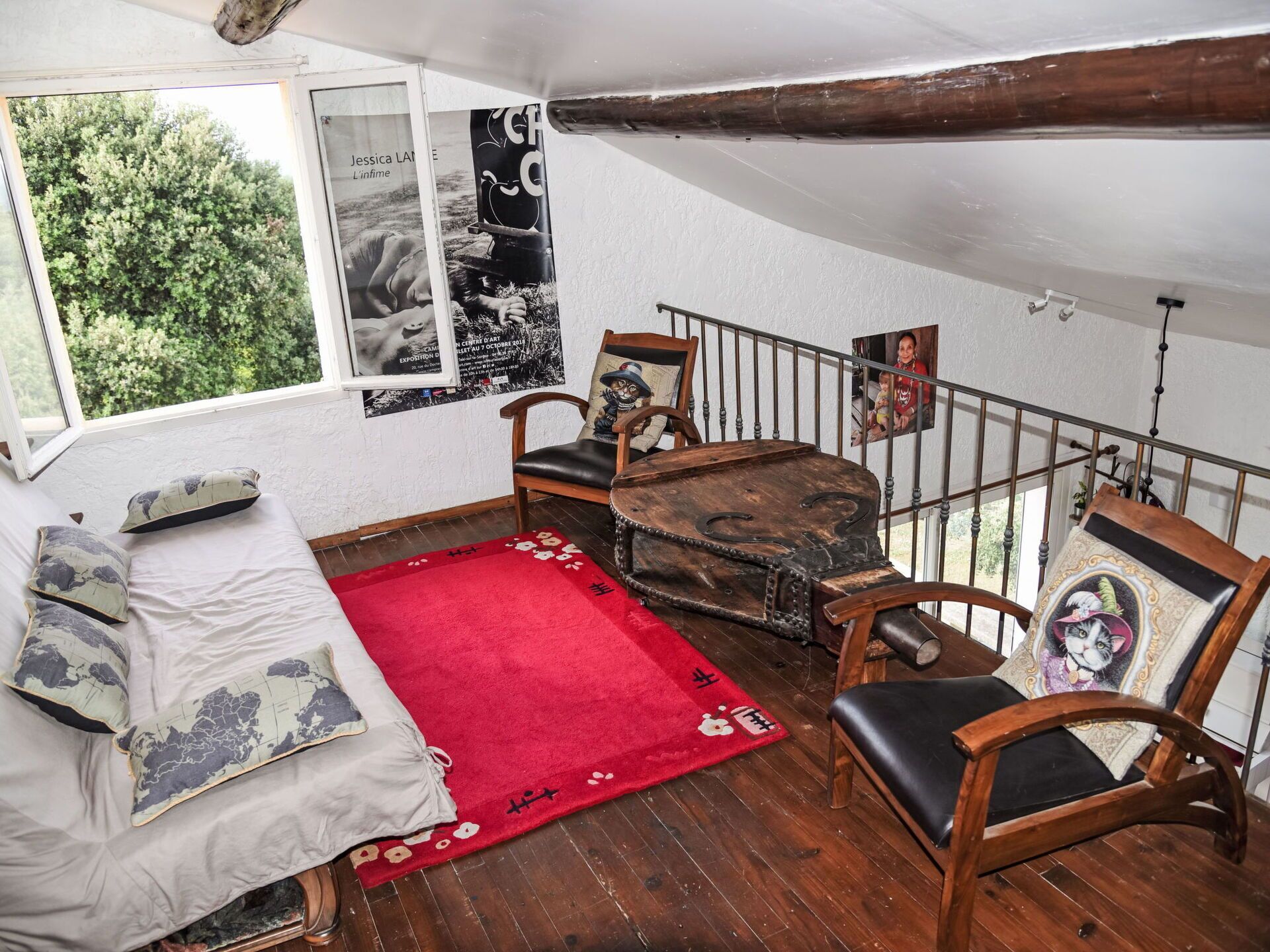 Ein gemütliches Zimmer mit einem Bett, einem roten Teppich, Holzstühlen und einem Holztisch.