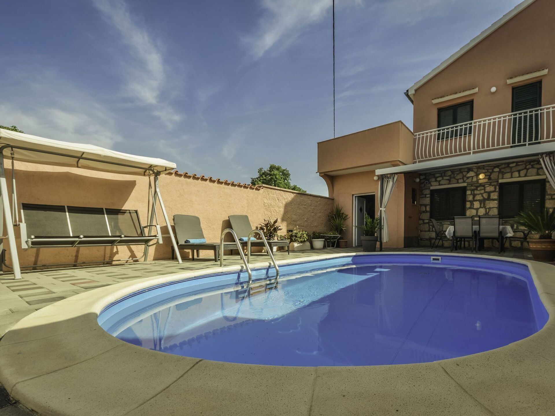 Una piscina con sillas de descanso y un porche cubierto.