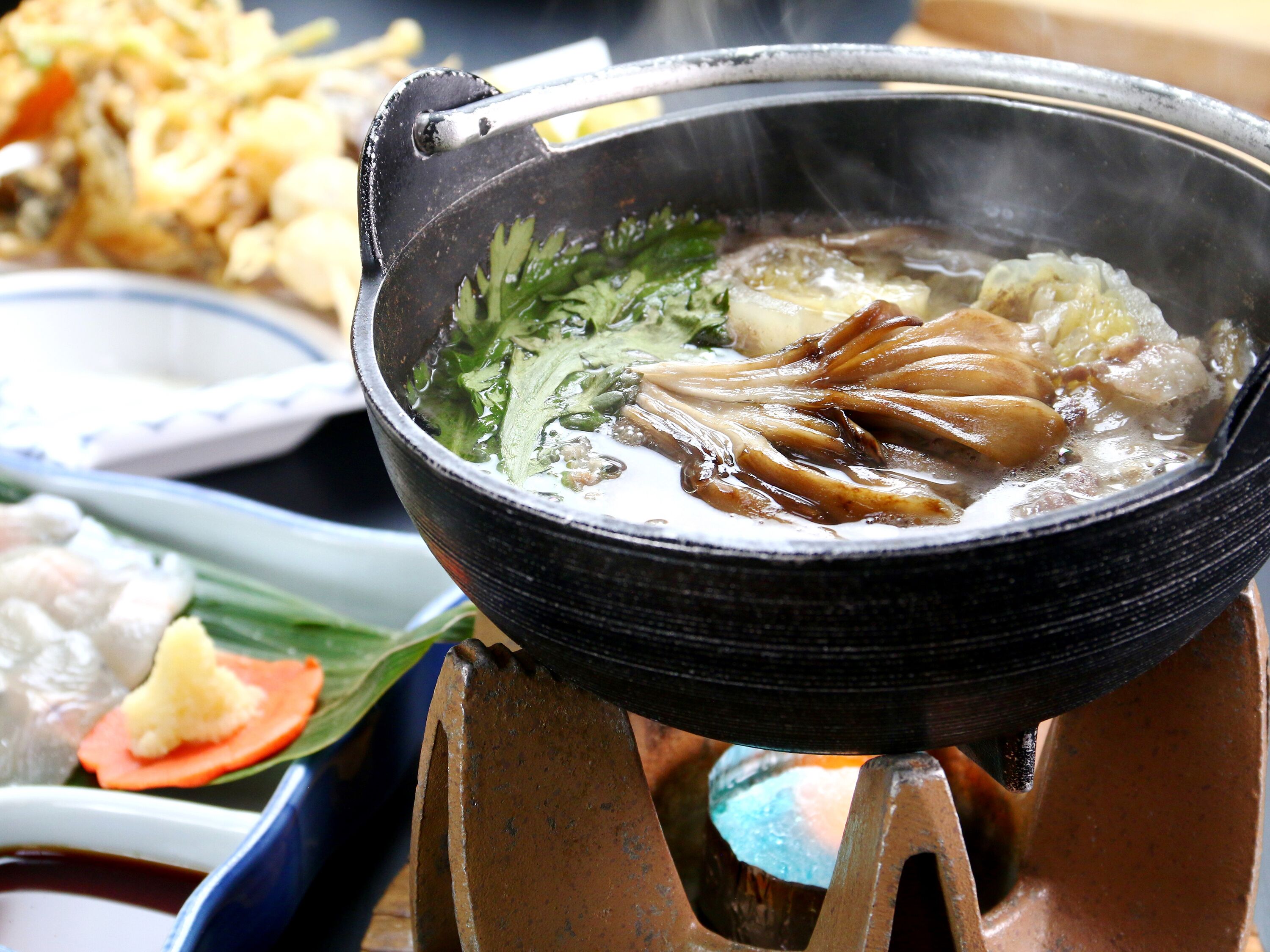 A hot pot with various ingredients simmering in a black pot on a stove.
