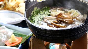 A hot pot with various ingredients simmering in a black pot on a stove.