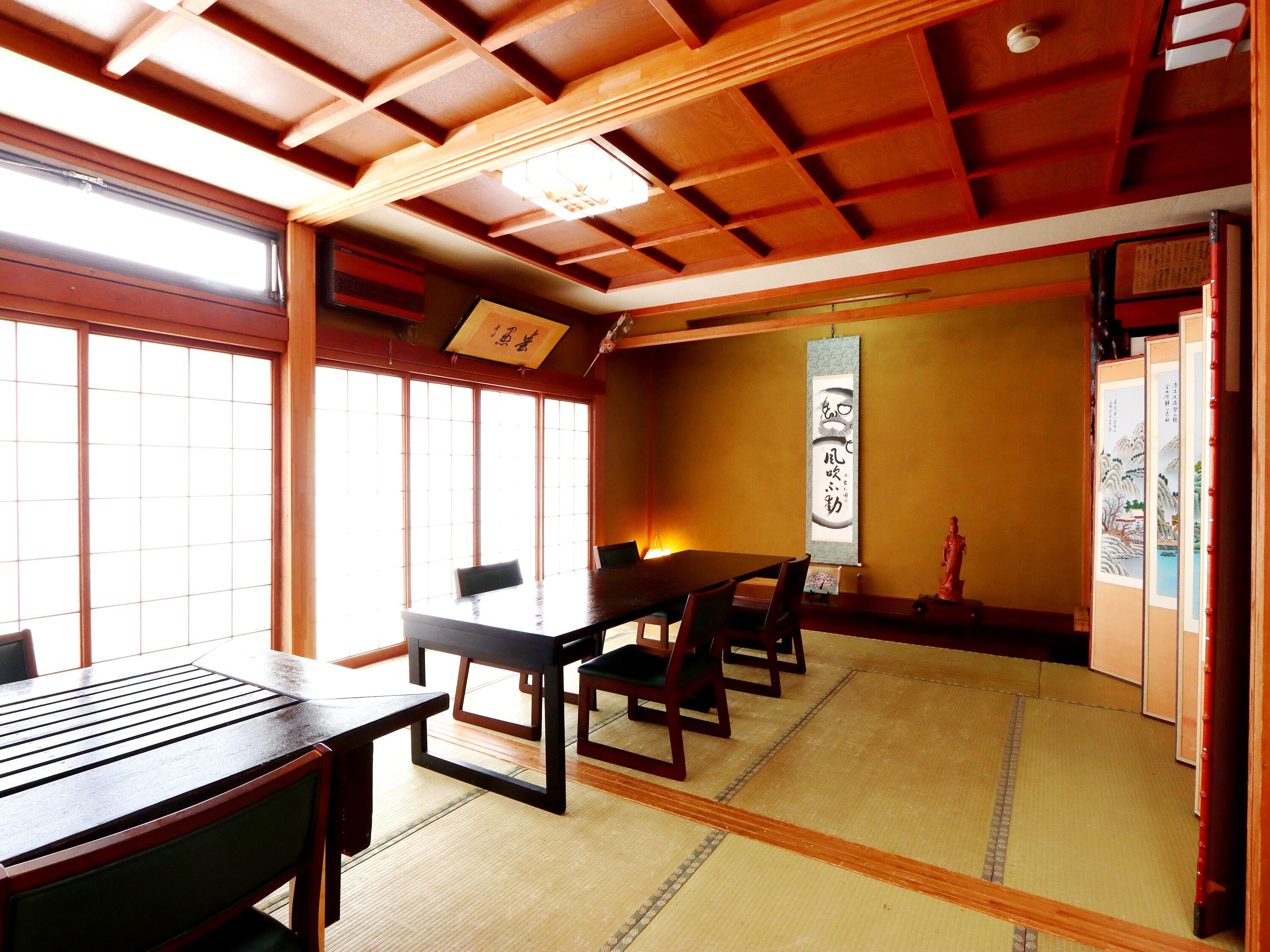 A traditional Japanese room with tatami flooring, a low table, and chairs.