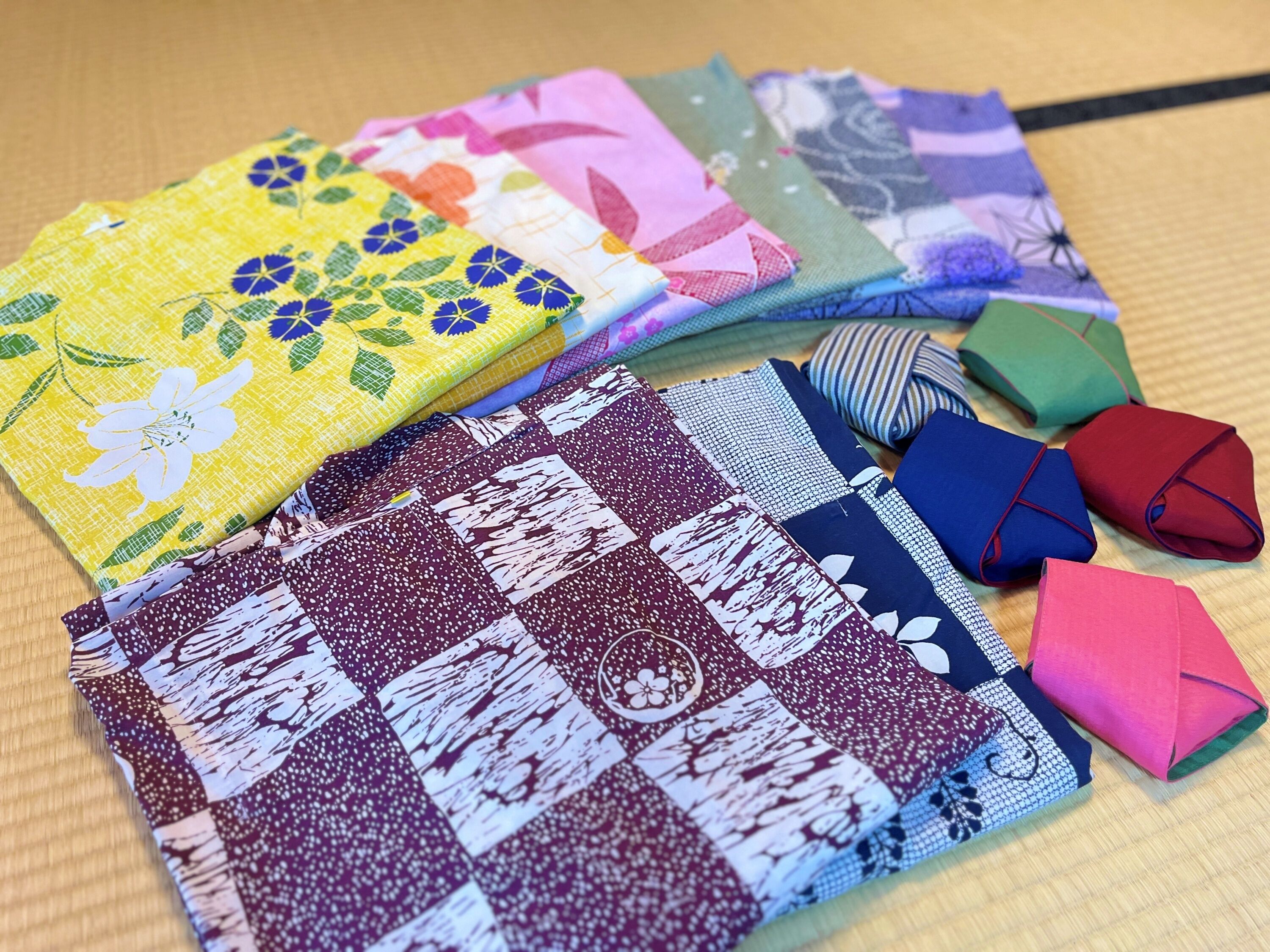 A variety of colorful fabrics laid out on a wooden surface.