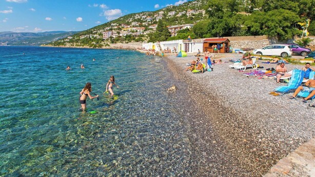 A pebble beach with clear water, people swimming, and beach chairs. - Lovely apartment for 4 people with WIFI, pool, TV, terrace and pets allowed (Senj)