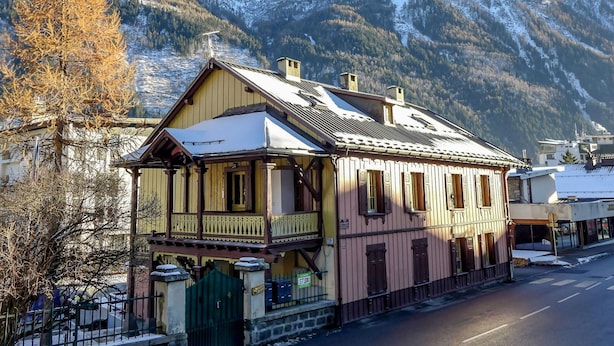 A traditional wooden house with a balcony, set against a backdrop of snow-covered mountains. - Cosy apartment for 4 people with hot tub, WIFI and TV (Chamonix)