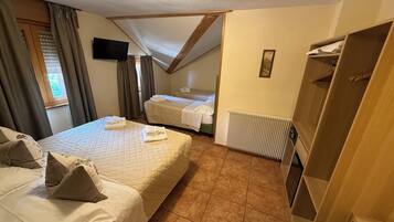 Une chambre d’hôtel avec deux lits, une télévision, un radiateur et une armoire.